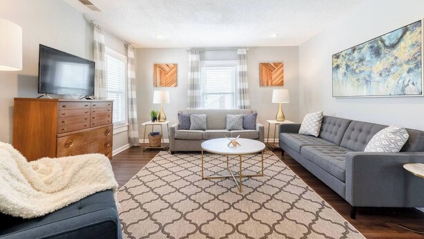 A modern living room with a sofa, a coffee table, and a TV. - Relaxing 2BR Getaway Near KU Med with Pool | 18 (Kansas City)