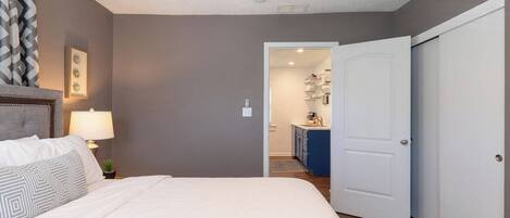 Un dormitorio con cama, mesita de noche, lámpara y ventilador de techo.