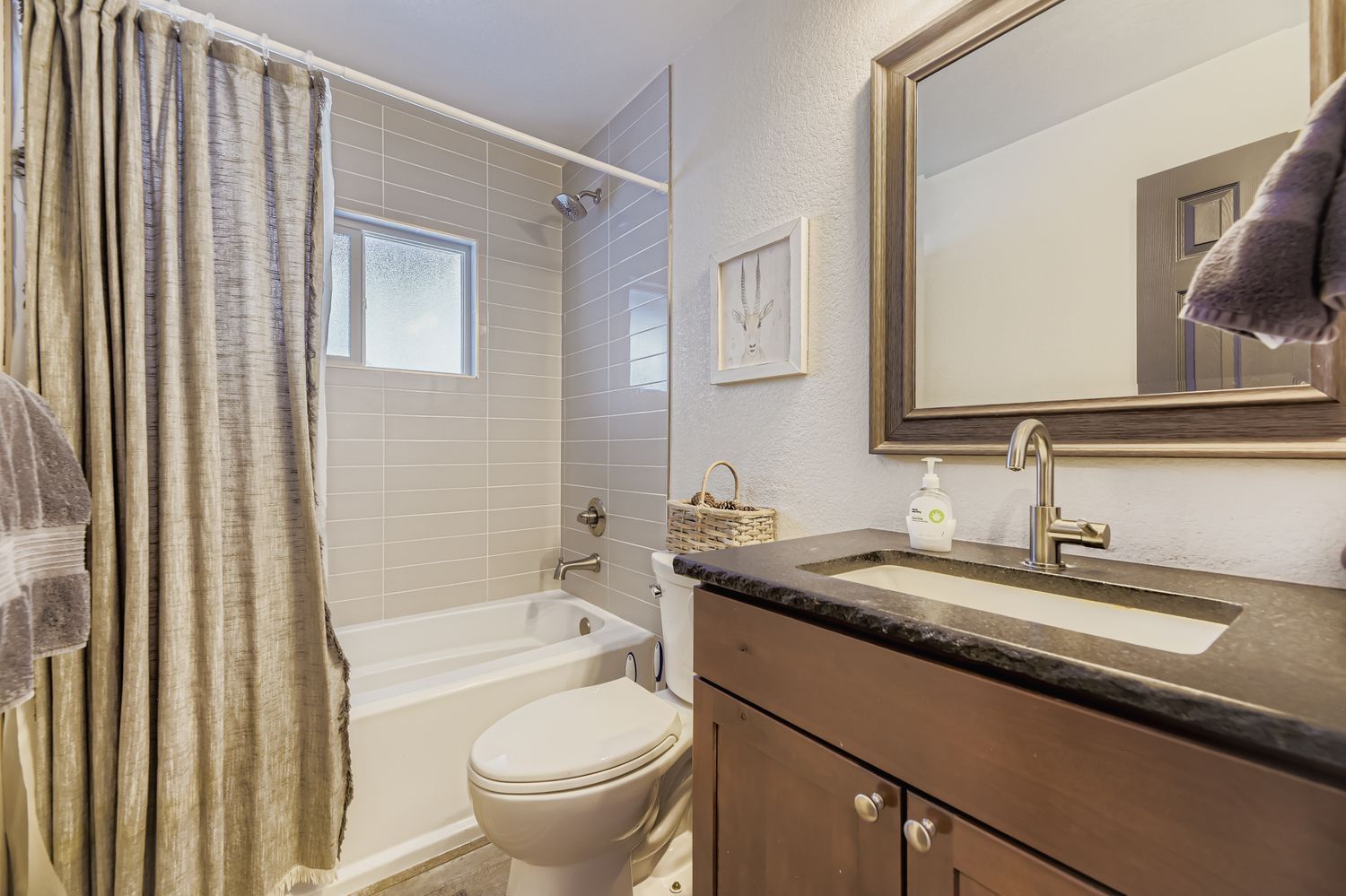 A bathroom with a bathtub, toilet, vanity, and a large mirror.