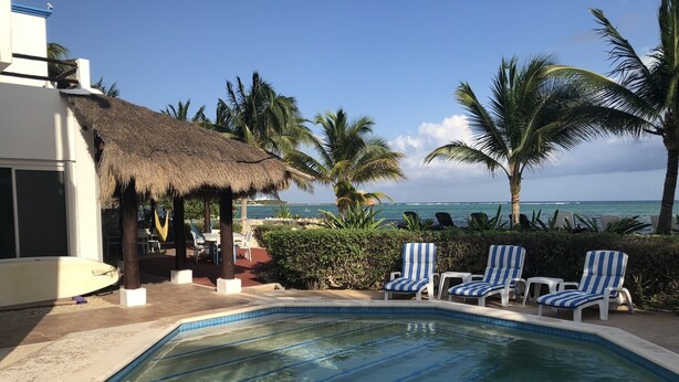 A swimming pool with lounge chairs, a thatched-roof structure, and a view of the ocean. - Spacious Beachside Villa with Outstanding Meals, Pool, WiFi – Large Sandy Beach (Tankah Tres)