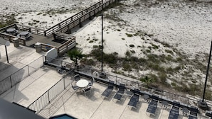 A beach view with a wooden walkway, lounge chairs, and umbrellas.