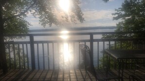A wooden deck with a metal railing overlooking a body of water. - Love Sunsets?   Glory in a natural, cozy,  rustic setting (Huddleston)
