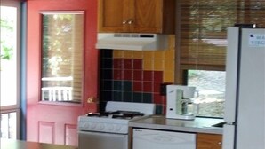 A compact kitchen with wooden cabinets, a white stove, and a refrigerator. - Love Sunsets?   Glory in a natural, cozy,  rustic setting (Huddleston)