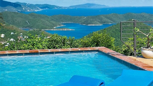 Una piscina con vista a un paisaje montañoso y una masa de agua.