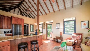 Una cocina amplia con armarios de madera, una isla grande con taburetes y un ventilador de techo.