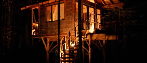 A wooden cabin with a spiral staircase, windows, and a porch.