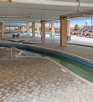 An indoor swimming pool area with tiled flooring, lounge chairs, and a clear view of the pool.
