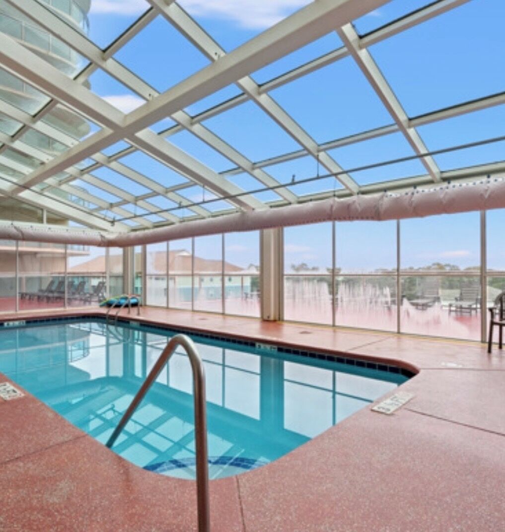 An indoor swimming pool with clear glass ceilings and a view of the surrounding landscape.