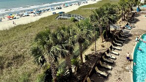 Een strandresort met een zwembad, strandparasols en palmbomen.