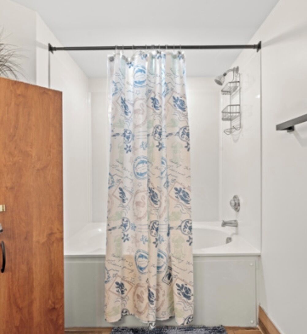 Een badkamer met douchegordijn met een paisley patroon, een badkuip en een houten deur.