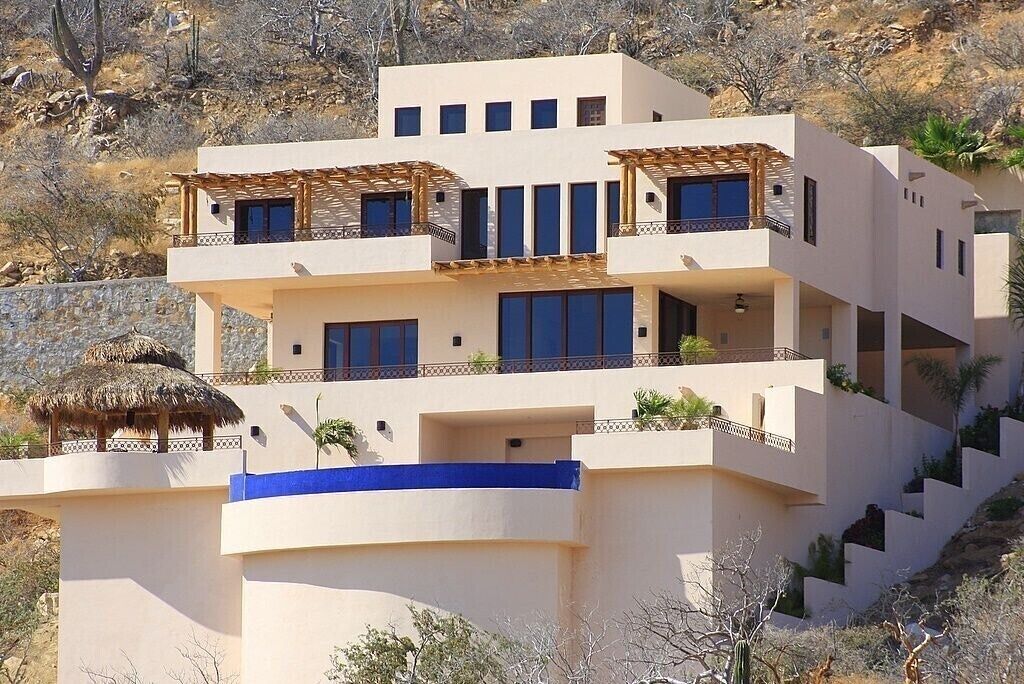 A multi-story building with balconies, a thatched-roof structure, and a blue railing.