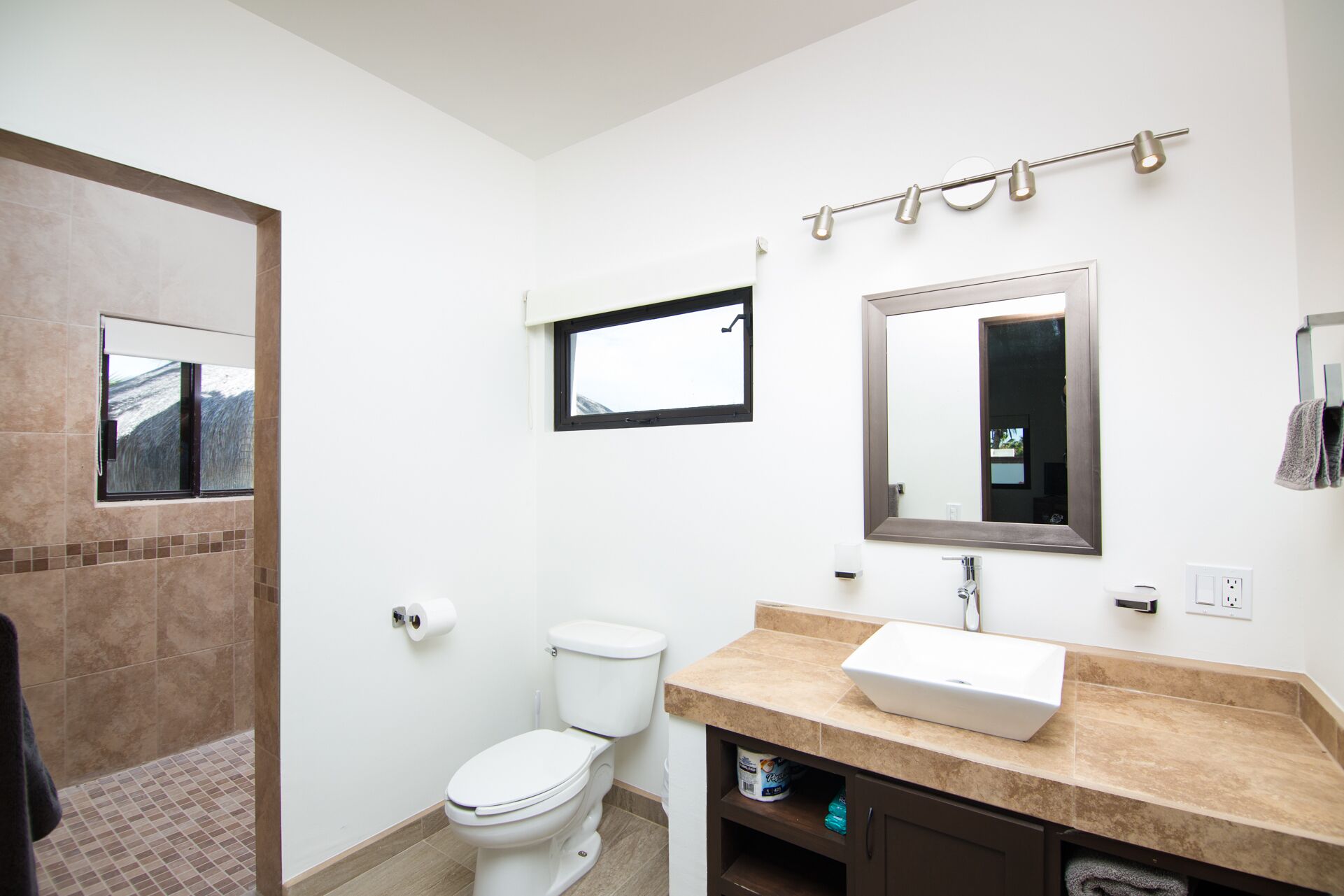 Une salle de bain équipée de toilettes, d’un lavabo, d’un miroir et d’un porte-serviettes.