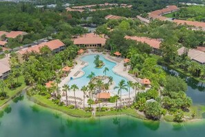 A resort with a central swimming pool, surrounded by palm trees and lounge areas. - Bahama Breeze @Falling Waters Naples, Florida (Naples)