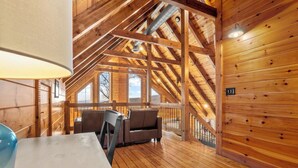 A wooden interior with a high ceiling, wooden beams, and a seating area with a table and chairs. - Lookout Lodge (Bryson City)