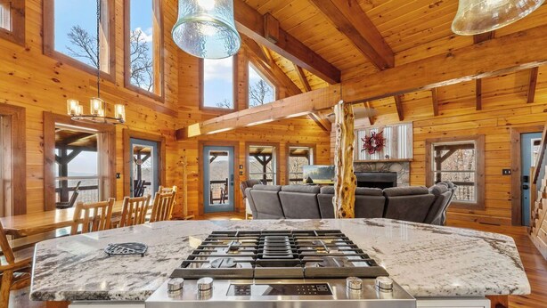 A spacious kitchen with a large island, wooden walls, and a high ceiling. - Lookout Lodge (Bryson City)