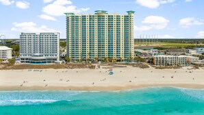A beachfront hotel with multiple high-rise buildings, a sandy beach, and a clear blue sky. - 2 Bedrooms in Aqua Resort - Remodeled with amazing views! Beach chairs included! (Panama City Beach)