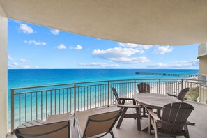 Un balcon avec vue sur l’océan et une jetée, aménagé avec une table et des chaises.