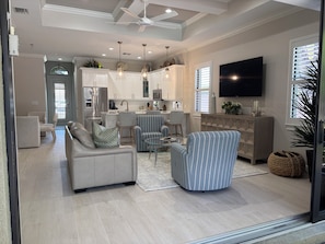 A modern living room with a sofa, armchairs, a coffee table, and a TV.