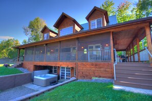A wooden cabin with a covered deck, a hot tub, and a staircase leading to a second level. - adirondack style all season lodge/resort on a natural glacier pond- SPECIAL RATE (Granville)