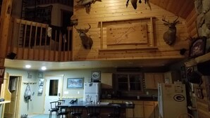 Interior de una cabaña con paredes de madera, un comedor y monturas de animales.