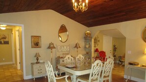 A dining area with a round table, white chairs, and a chandelier. There are wall-mounted mirrors and a red chair in the background. - Elegant & Spacious Home!! 5 Bed & 3 Bath, 15 min. to U of O, Sleeps 14, 174.00 (Creswell)