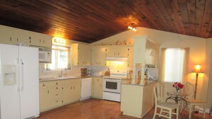 A kitchen with wooden floors, white cabinets, a stove, and a dining area with a chair and table. - Elegant & Spacious Home!! 5 Bed & 3 Bath, 15 min. to U of O, Sleeps 14, 174.00 (Creswell)