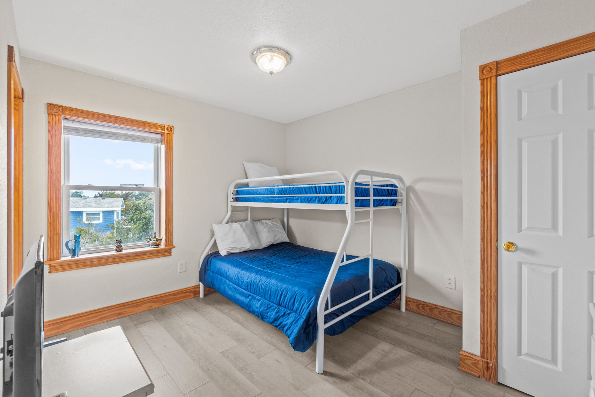Une chambre avec un lit superposé, une fenêtre, une porte et un luminaire au plafond.