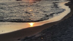 Une plage avec des vagues et un coucher de soleil.
