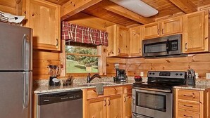 Una cocina con armarios de madera, electrodomésticos de acero inoxidable y una ventana con vistas al verdor.