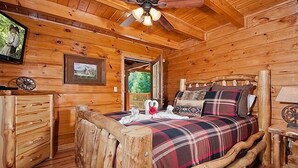 Un dormitorio de cabaña de madera con cama, cómoda y ventilador de techo.