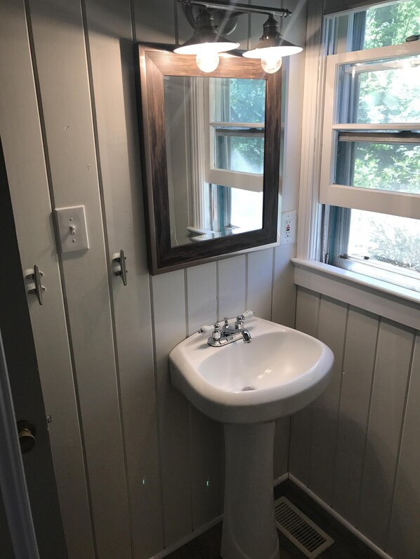 A bathroom with a white sink, a mirror, and a window. - Lake Front Cabin W/ Screened-in Porch and personal dock - Close for Auburn games (Dadeville)