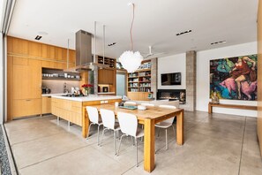 Una cocina moderna con armarios de madera, una isla central y sillas blancas.