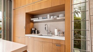 A modern kitchen with wooden cabinets, a stainless steel sink, and a built-in shelf with kitchenware.