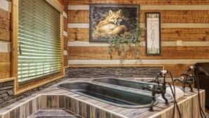 A rustic cabin interior with a wooden wall, a framed fox painting, a welcome sign, and a stone fireplace. - Secluded Studio Cabin Rental-Honeymoon/Anniversary Getaway-dog Friendly (Pigeon Forge)