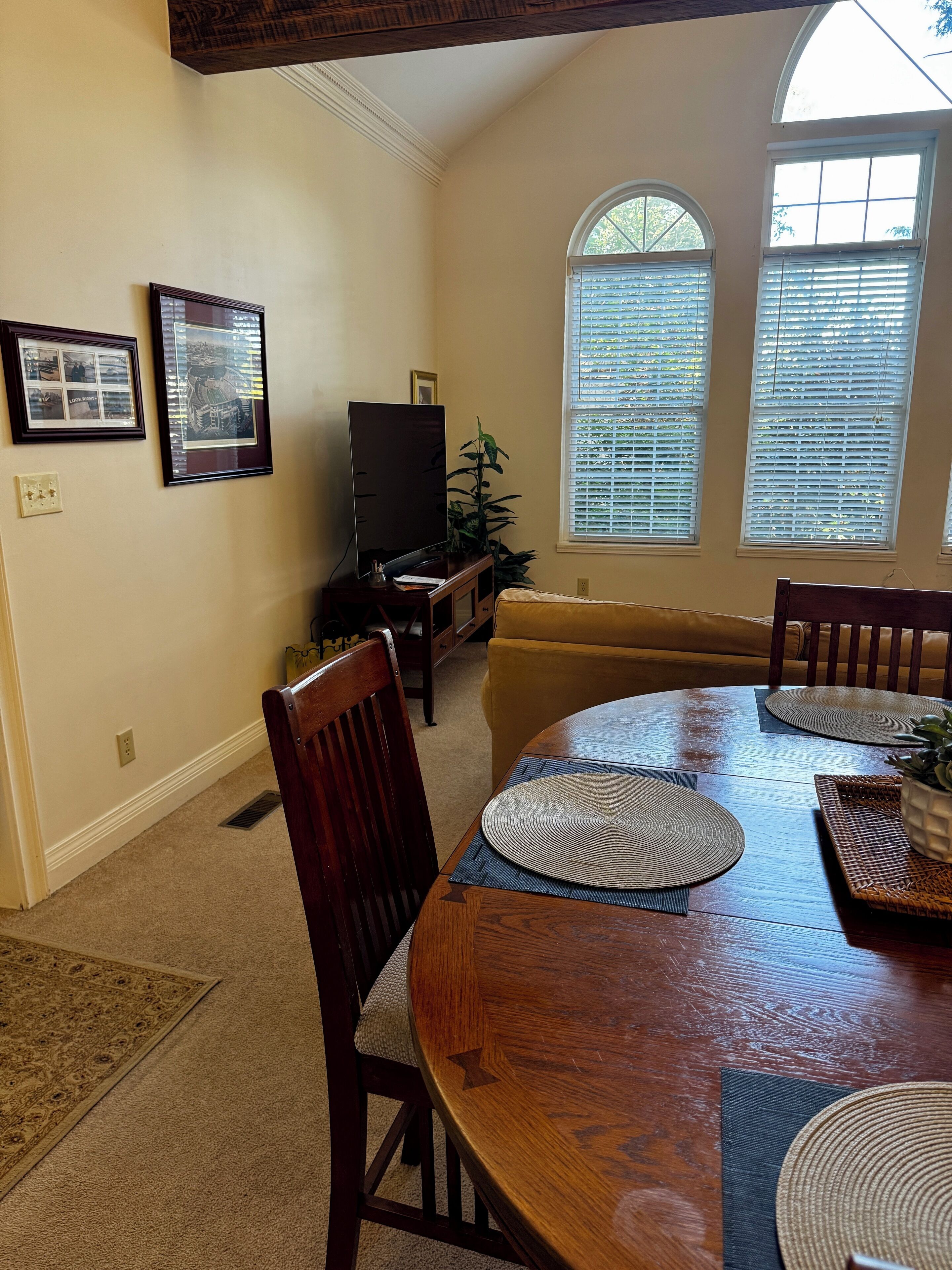 A dining area with a wooden table, chairs, and a television in the background.