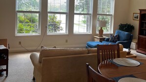Ein geräumiges Wohnzimmer mit großem Fenster, Deckenventilator und Essbereich mit Tisch und Stühlen.