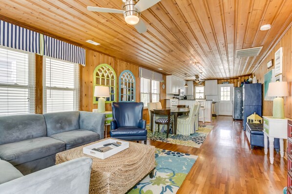 A spacious living room with a gray sofa, a blue armchair, and a woven coffee table.