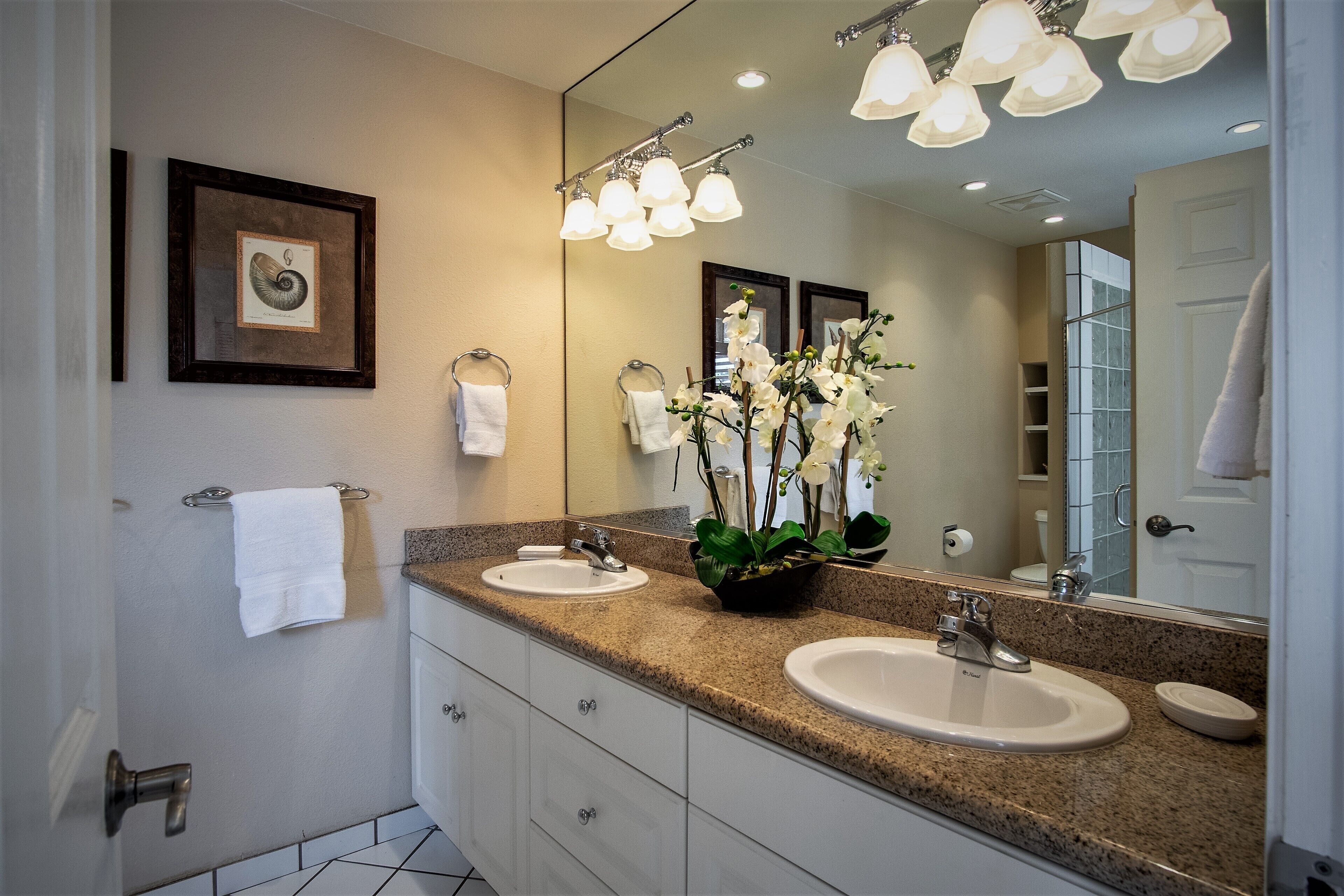 A bathroom with two sinks, a large mirror, and a framed picture on the wall.