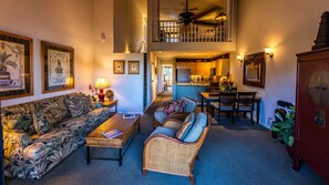 A spacious living room with a high ceiling, a dining area, and a kitchen.