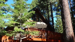 A wooden cabin with a balcony and a large umbrella. -  5-Star Tahoe Chalet with Hot Tub in Quiet Setting (South Lake Tahoe)