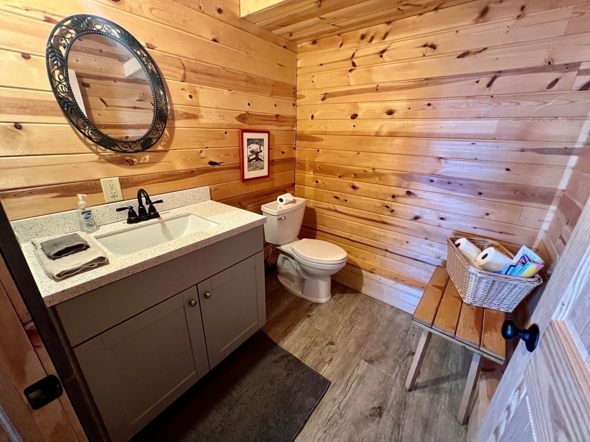 Een houten badkamer in een vakantiehuisje, met een wastafel, toilet en spiegel.