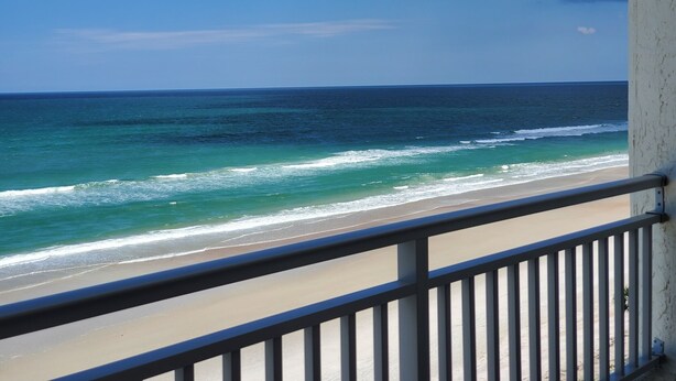 Ein Balkon mit Blick auf das Meer und den Strand.