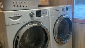 Una lavadora Bosch con una cesta encima, en una habitación con armarios de madera y una ventana.