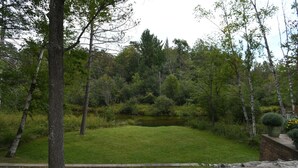 Un jardín ajardinado con un estanque, rodeado de árboles y un sendero de piedra.