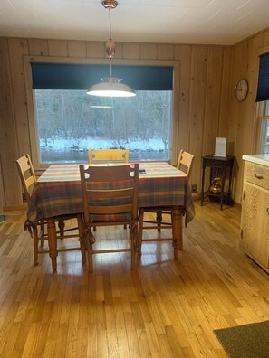 Enjoy meals in this dining area with a table for four, featuring a plaid tablecloth and a view of the surrounding landscape.