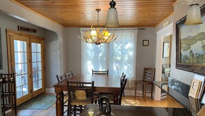 Un coin repas avec une table en bois, des chaises, un lustre et un tableau au mur.