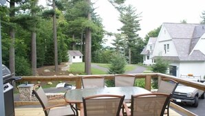Une terrasse en bois avec une table et des chaises, donnant sur un quartier résidentiel avec des maisons et des arbres.