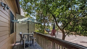 Een houten terras met een tafel, stoelen en een parasol, en een Amerikaanse vlag.