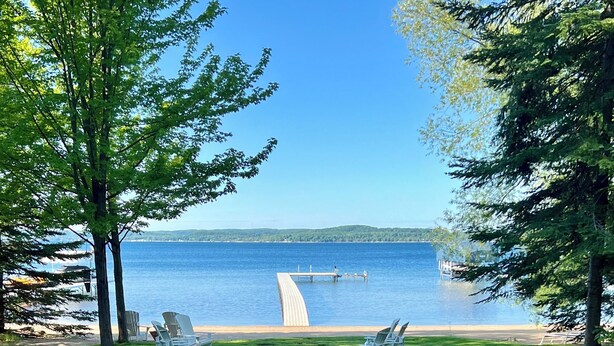 A grassy pathway leading to a dock over a lake, with chairs and a clear view of the water. - Beautiful Lake Charlevoix Sandy Beach- Best North Shore Location (Boyne City)