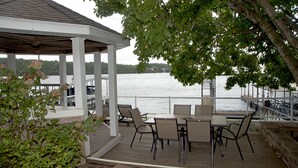 A covered outdoor seating area with tables and chairs, overlooking a body of water.